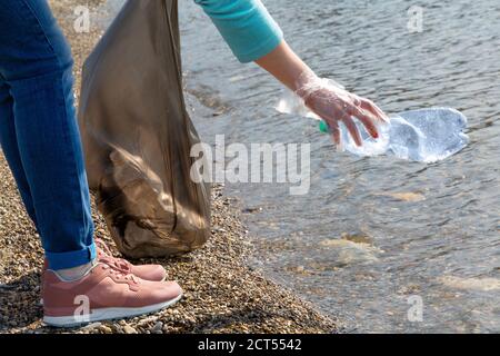 Volunteer zieht eine Plastikflasche aus dem Meer. Konzept der Erhaltung der Ökologie und der Umweltreinheit. Stockfoto