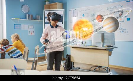 Nettes Mädchen trägt Augmented Reality Headset und mit Controllern interagiert mit 3D-Sonnensystem. Futuristische Schule Wissenschaft Klasse für Kinder Stockfoto
