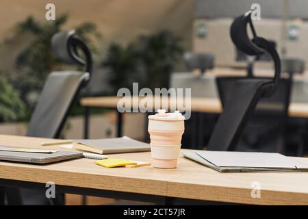 Nahaufnahme Hintergrundbild von modernen offenen Raum Büro mit Pflanzen dekoriert, konzentrieren sich auf Kaffeetasse auf Holztisch im Vordergrund, kopieren Raum Stockfoto