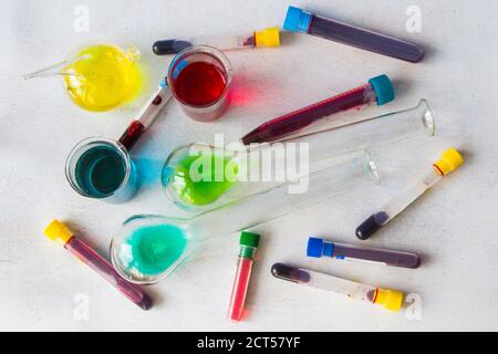 Laborglas mit farbigen Reagenzien auf weißem Hintergrund und Blutproben Stockfoto