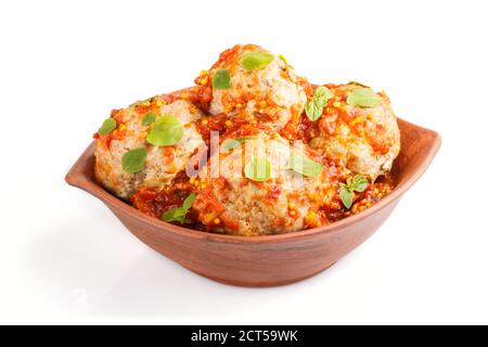 Fleischbällchen aus Schweinefleisch mit Tomatensauce, Oregano-Blättern, Gewürzen und Kräutern in Tonschüssel isoliert auf weißem Hintergrund. Seitenansicht, Nahaufnahme. Stockfoto