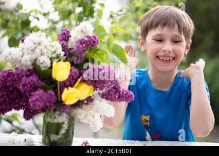 Fröhliches Kind mit einem Blumenstrauß. Glücklicher Junge im Sommer. Stockfoto