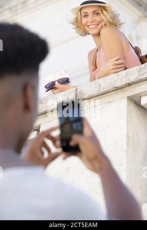 Junger Mann fotografiert Freundin im Freien Stockfoto