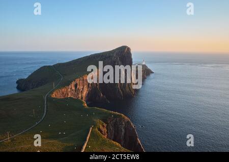 Eine Landschaft eines feinen Leuchtturms, der auf einer atemberaubenden Klippe vor der Kulisse des Meeres und des Sonnenuntergangshimmels steht. Neist Point, Isle of Skye, Schottland. Stockfoto