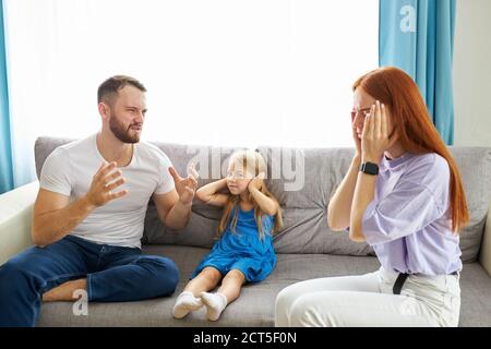 kaukasische Kind Mädchen leidet unter Streitigkeiten zwischen Eltern in der Familie zu Hause, Rothaarige Frau und bärtigen Kerl argumentieren in Anwesenheit von Tochter Stockfoto