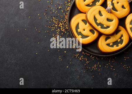 Halloween Lebkuchen Kekse auf schwarzem Hintergrund. Lustige Kürbisgesichter. Stockfoto