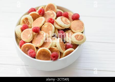 Köstliche frisch gekochte hausgemachte Mini Pfannkuchen mit Himbeeren. Trendiges Essen. Aussicht von oben. Frühstück für Kinder. Stockfoto