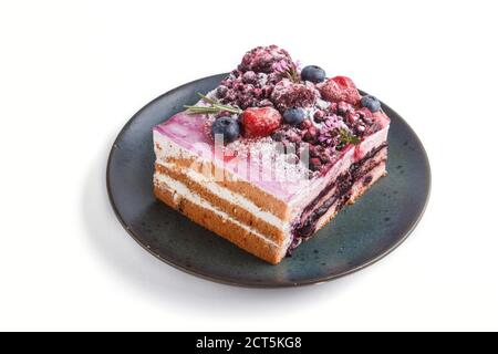 Beerenkuchen mit Milchcreme und Heidelbeermarmelade auf blauer Keramikplatte isoliert auf weißem Hintergrund. Seitenansicht, Nahaufnahme. Stockfoto