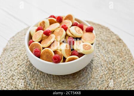 Köstliche frisch gekochte hausgemachte Mini Pfannkuchen mit Himbeeren. Trendiges Essen. Aussicht von oben. Frühstück für Kinder. Stockfoto