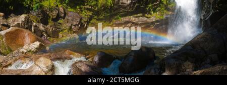 Panoramafoto des Regenbogens bei Wainui Falls, einem Wasserfall in der Golden Bay Region, Südinsel, Neuseeland Stockfoto