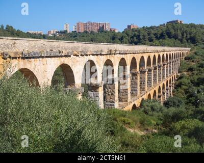 Antikes römisches Aquädukt, bekannt als El Pont del Diable (Teufelsbrücke) und die Wohnhäuser am Horizont in Tarragona, Katalonien, Spanien. Stockfoto