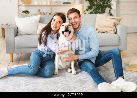 Junge glückliche Ehegatten mit Hund posiert zu Hause Stockfoto