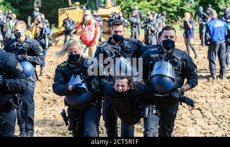 Hessen, Deutschland. September 2020. 21. September 2020, Hessen, Homberg (Ohm): Polizeikräfte tragen einen Aktivist, der ein Raupenfahrzeug besetzt hatte, weg. Derzeit wird ein Bereich vorbereitet, auf dem nach Angaben der Polizei die Baumaschinen für den Bau der A49 abgestellt werden sollen. Aktivisten wehren sich gegen den weiteren Bau der Autobahn 49 im Dannenröder Wald. Foto: Andreas Arnold/dpa Quelle: dpa picture Alliance/Alamy Live News Stockfoto