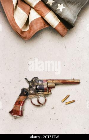 Alte Revolver Pistole mit Kugeln auf einem Betonhintergrund mit Vintage amerikanische Flagge Stockfoto