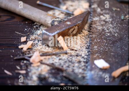 Alter Vintage Hammer, Holzsäge, Nägel und Sägemehl auf Holzhintergrund, Nahaufnahme, selektiver Fokus Stockfoto