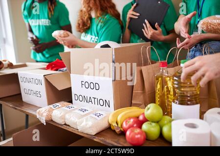 Diverse Freiwillige sammeln Lebensmittel und Kleidung Spenden im Lager, multi-ethnischen Team von Freiwilligen hält Spenden Boxen in einem großen Lager, t Stockfoto