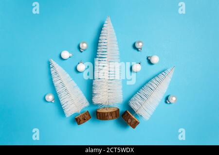 Drei weiße Weihnachtsbäume und weiße und silberne Kugeln auf blauem Hintergrund. Minimale Winter flach lag. Weihnachtsferien und Winterkonzept Stockfoto
