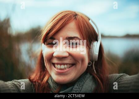 Junge Frau, die ein Selfie mit ihrem Smartphone in der Nähe eines see Stockfoto