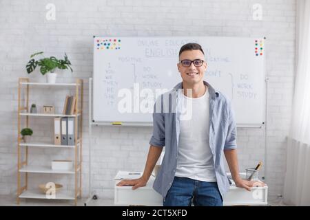 Online Englischschule und moderne Lehrer aus der Ferne. Moderner lächelnder Tutor mit Brille schaut auf die Kamera und macht Videos für Studenten Stockfoto