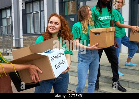 Interracial Gruppe von Freiwilligen, die auf humanitäre Hilfe-Projekt, im Freien. Gemischte rassenfreundliche Menschen arbeiten in wohltätigen Stiftung, halten Boxen Stockfoto