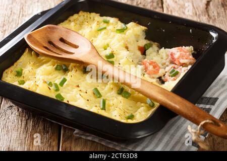 Heißer herzhafter Kuchen aus Kartoffelpüree, Sahne, Zwiebeln und Lachs in einer Auflaufform auf dem Tisch. Horizontal Stockfoto