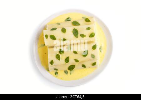 Cannelloni Pasta mit Eiersauce, Frischkäse und Oregano-Blätter isoliert auf weißem Hintergrund. Draufsicht, flach liegend, Nahaufnahme. Stockfoto