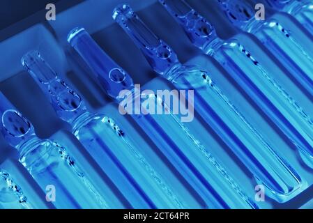 Nahaufnahme der Ampullen-Reihe in der Packung in ultraviolett Beleuchtung mit selektivem Fokus Stockfoto