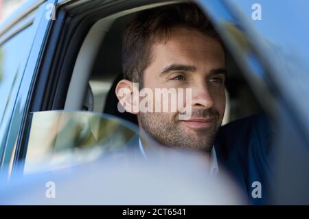 Junger Mann, der während seines morgendlichen Pendelvorgangs in seinem Auto sitzt Stockfoto
