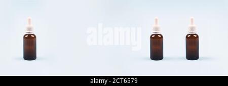 Banner mit Tropfflaschen mit ätherischem Öl, Kollagen oder Hyaluronsäure auf hellblauem Hintergrund. Mockup und Copyspace für Ihr Design oder Text Stockfoto