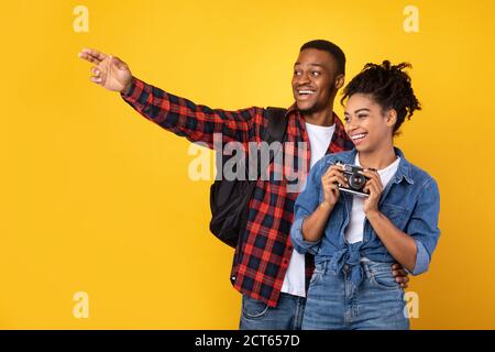 Afrikanisches Paar Mit Fotokamera, Die Bilder Auf Gelbem Hintergrund Nimmt Stockfoto