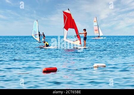 Bodrum, Türkei - August 2017: Kleine Kinder und Jugendliche machen Surfübungen während des Windsurfunterrichts in Bodrum, Gumusluk, Türkei Stockfoto