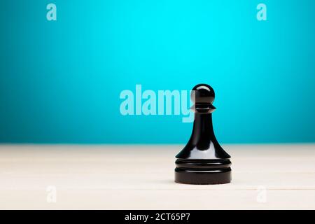 Eine schwarze Schachfigur auf Holztisch gegen Blau Hintergrund mit Kopierbereich Stockfoto