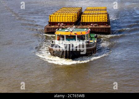 Schlepper ziehen Fracht als Container in einem separaten großen Barge entlang der Themse in London Stockfoto