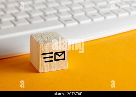 E-Mail-Symbol auf Holzblock mit Computer-Tastatur Hintergrund auf gelb. Kundenbetreuung, Support oder E-Mail-Messaging-Konzept. Stockfoto