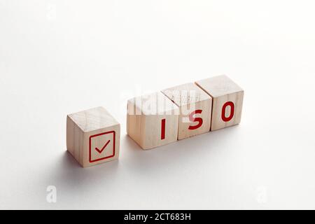 Die Abkürzung ISO auf Holzwürfeln mit Häkchen auf weißem Hintergrund. ISO Qualitätskontrolle Zertifizierung Zulassungs Konzept. Stockfoto