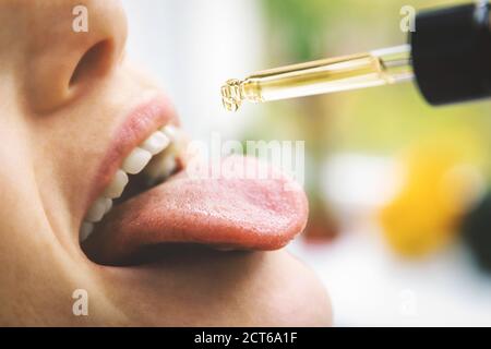 Pflanzliche alternative Medizin und Nahrungsergänzungsmittel - Frau, die CBD Hanföl Tropfen im Mund von Tropf. Medizinisches Cannabis Stockfoto