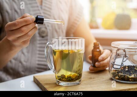 Nahrungsergänzungsmittel und Vitamine - Frau Zugabe Tropfen CBD-Öl in Tasse Tee mit Pipette. Anti-Stress Stockfoto