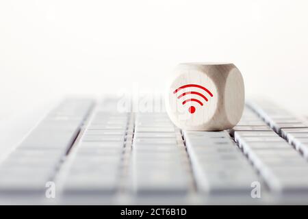 WiFi-Symbol auf Holzwürfel auf Computer-Tastatur vor weißem Hintergrund. Wi-Fi-Verbindung mit Computer, Fernunterricht oder Online-Bildungskonzept Stockfoto