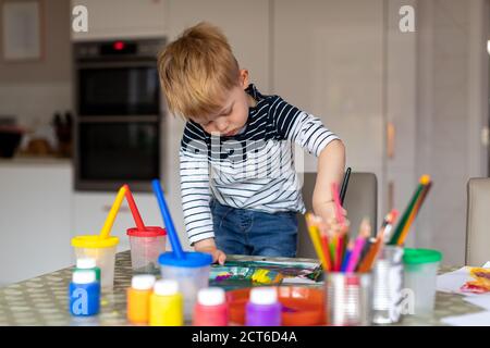 Drei Jahre alter Junge beschäftigt Malerei zu Hause, mit Farbtöpfen und Bürsten. Stockfoto