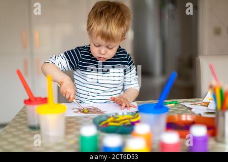 Drei Jahre alter Junge beschäftigt Malerei zu Hause, mit Farbtöpfen und Bürsten. Stockfoto