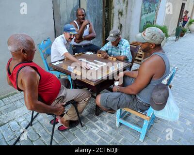 LEUTE, DIE AUF DER STRASSE AN EINEM TISCH SITZEN UND DOMINOSTEINE SPIELEN, NATIONAL SPIEL Stockfoto