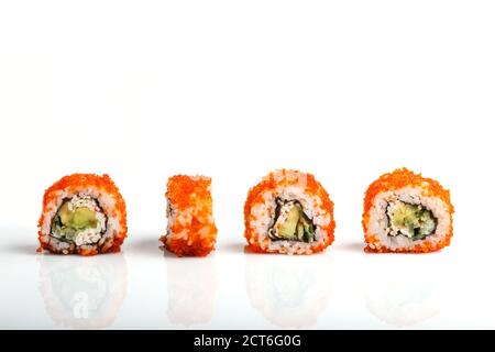 Vier japanische Maki-Sushi-Rollen in einer Reihe mit fliegenden Fischrogen, Avocado und Gurken isoliert auf weißem Hintergrund. Seitenansicht, Nahaufnahme. Stockfoto