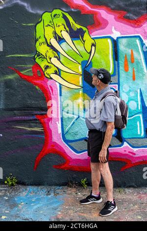 Älterer, älterer Mann und farbenprächtiger Wandabschnitt mit grünen Händen und Klauen-ähnlichen Nägeln im Mauer Park, Prenzlauer Berg, Berlin. Stockfoto