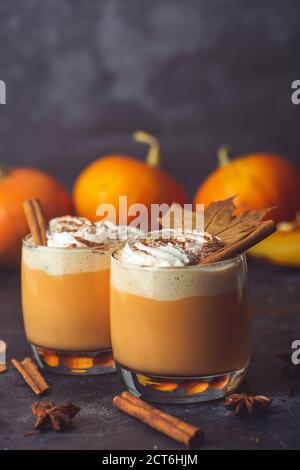 Kürbis Latte Getränk. Herbstlicher Kaffee mit würzigem Kürbisgeschmack und Sahne auf dunklem Hintergrund. Saisonale Herbstgetränke zu Halloween und Thanksgiving Stockfoto