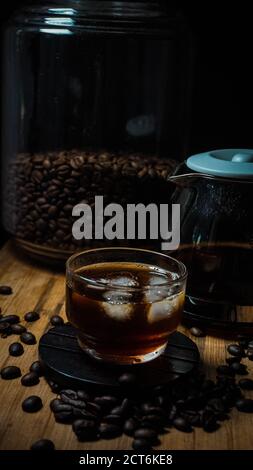 Schwarzer Eiskaffee im Glas und Kaffeebohnen Stockfoto