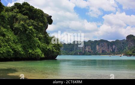 Steile Kalksteinklippen, die hoch über dem Wasser am Railay West Beach in der Provinz Krabi, Thailand, ragen Stockfoto