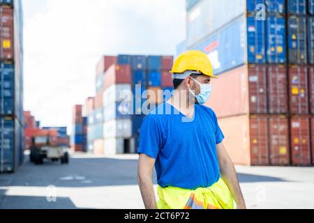 Containerarbeiter mit Schutzmaske zum Schutz vor Covid-19-Arbeiten am Frachtcontainer. Stockfoto