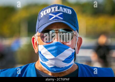 Scottish Independence Supporter trägt eine Saltire Gesichtsmaske ein Baseball-Cap Logo'ed Schottland und Sonnenbrille, bei einer politischen Unabhängigkeitskundgebung aufgenommen, Stockfoto