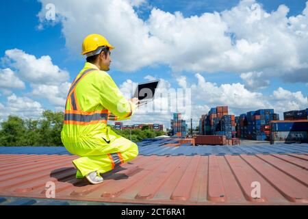 Ingenieur Arbeiter in schützende Sicherheit Jumpsuit Uniform verwenden Laptop-Computer Überprüfung Produkt im Frachtcontainer Versandlager. Stockfoto