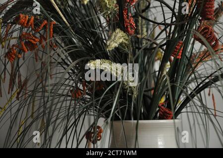 Blumenarrangement. Anordnung von bunten, unnatürlichen Blüten in Keramikvase, mit selektivem Fokus und verschwommenem Hintergrund Stockfoto